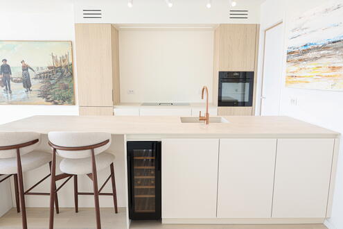 Frontaal zicht op moderne keuken met schiereiland en houten kastenwand